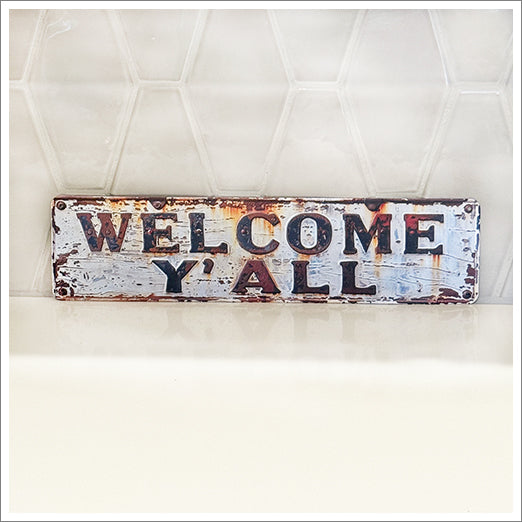 Greet your guests in Southern Style with this darling sign! 2-D printed with a vintage finish on an aluminum sheet. Distressed ivory background with rust accents and distressing. Very lightweight, yet sturdy. The letters are NOT raised, although the illusion is that they are. The graphic is sublimation printed, no actual texture. It has a smooth finish.
Holes drilled at the corners for hanging. (Screws not included.)
Perfect size at 15.5" wide x 4" tall